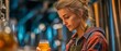 © tongpatong - A freshly made craft beer is examined and tasted by a female brewmaster.  Her method of quality control in a contemporary brewhouse