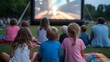 © Ch - Joyful families gather on picnic blankets for a magical outdoor movie night under the twilight sky, creating cherished summer memories together.