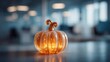© Igor - Collaborative office environment Halloween decoration with miniature glowing glass pumpkin on workspace surface featuring warm amber light and modern blurred office background