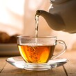 © lembut - A clear glass cup being filled with steaming tea from a white teapot