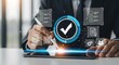 © Fatma - Business professional interacting with a digital interface displaying a verified checkmark and various icons representing business processes and data analysis on a tablet screen