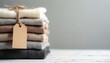 © Maryna - Stack of soft cashmere sweaters in neutral colors tied with twine. Blank tag on pile implies price or branding options for winter apparel, fashion retail.