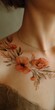 © Yuliia - Elegant floral tattoo featuring orange poppies and botanical elements on collarbone area, complemented by delicate gold chain necklace. Warm-toned artistic body art.