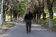 © Midea  - A man is walking down a tree-lined path