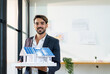 © PINA - male architect engineer raising house model with solar panel standing near window, caucasian man holding model smiling for new idea real estate property innovation while working at office