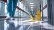 © Ilmi - Janitor Wiping Floor in Hospital Corridor Near Nurse Station with Caution Sign for Safety Awareness