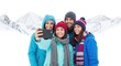 © sambath - Four friends taking a selfie in a snowy landscape.