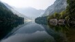 © Mitchell - Serene mountain lake mirrors misty peaks and lush evergreen forests under a tranquil, overcast sky, evoking peaceful escapism.