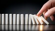 © Mitchell - Hand initiating domino effect with white blocks, symbolizing cause, consequence, and momentum in business or strategy