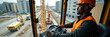 © AlenaSi - Crane operator at work controlling machinery on building site, inside cabin with steering wheel. Crane operator wearing orange helmet and reflective vest, overseeing operations,