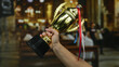 © Krakenimages.com - Man holding a golden trophy with ribbons inside a church, highlighting achievement and the significance of indoor celebrations.
