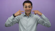 © Krakenimages.com - Young hispanic man in glasses smiles and gestures towards himself against a vibrant purple background creating an inviting isolated portrait with casual attire and positive expression