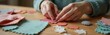 © Viktor - Female hands crafting with colorful fabric scraps on wooden table. Woman doing handmade creative work with textile and felt elements at workspace. Artistic hobby at home.