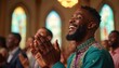 © Viktor - Joyful african american man claps hands during church service. He smiles broadly and wears a green shirt with gold and purple trim. People attend worship assembly in a sunlit cathedral.
