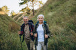 © sashafolly - Happy elderly family of man and woman with rucksacks during hike at hilly countryside