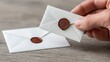 © elmyra - White envelopes with brown wax seals on a wooden surface.