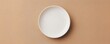 © donchanu - A single white ceramic oval plate resting on a textured tan surface dish