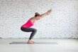 © junky_jess - Caucasian slim woman in pink sportswear practice chair pose indoor in loft fitness studio, Utkatasana.