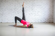 © junky_jess - Slim Caucasian 40 years old woman lying on back and does shoulder bridge exercise with one leg up in loft studio indoor.
