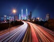 © Andrea - streaking light trails illuminate a highway leading to a vibrant city at night