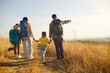 © Studio Romantic - Family hiking with backpack on nature trail. Parents guide children along a sunlit path as dad points to the horizon, enjoying outdoors and travel together. Concept family unity and adventure.