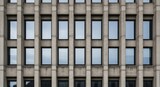 Geometric pattern of repeating rectangular windows on the facade of a modern concrete and glass office building