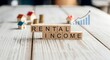 © ivatekstudio - Rental Income:  A visualization of rental income concept. Featuring miniature houses, stacked coins, and a rising graph, signifying financial growth, all arranged on a light wooden background.