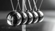 © Olga Gorkun - Newton cradle metal spheres in motion symbolizing physics principle, cause and effect, and the balance of energy in science, leadership, and decision-making
