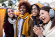 © Xavier Lorenzo - Group of young people having fun together during wintertime at a christmas market, drinking hot beverages and laughing