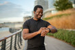 © Jelena - Black man smiling using smartwatch tracking fitness progress