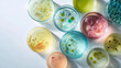 © fannybuddhies - Various petri dishes containing colorful bacterial cultures sit on a white surface, showcasing scientific research and laboratory experiments in a sterile environment.