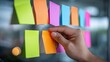 © Oleksandr - Brainstorming session with vibrant sticky notes! A hand carefully places a note on a wall, surrounded by colorful ideas. A visual reminder of collaboration.