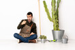 © luismolinero - Gardener man sitting on the floor at indoors frustrated and pointing to the front