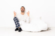 © luismolinero - Caucasian man in pajamas sitting on the floor at indoors in zen pose