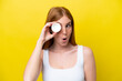© luismolinero - Young redhead woman isolated on yellow background with moisturizer and surprised