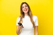 © luismolinero - Caucasian woman isolated on yellow background using mobile phone