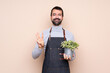 © luismolinero - Man holding a plant over isolated background happy and counting three with fingers