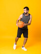 © luismolinero - Full-length shot of man over isolated yellow background playing basketball