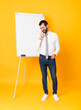 © luismolinero - Full-length shot of businessman giving a presentation on white board over isolated yellow background smiling a lot