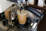 Closeup of espresso pouring from coffee machine in cardboard cup for take away. Shallow focus.