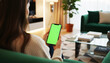 © MD Rashedul Islam - Hand holding smartphone with green screen in a bright contemporary living room, featuring minimalist furniture, soft natural lighting, cozy decor, and a modern stylish interior ideal for app or UI