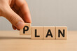 © Koushik - hand placing wooden block with letter p to complete the word plan representing business planning development strategy goals and objective setting