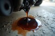© miss irine - Motor oil drips from car engine onto concrete floor. Dark liquid forms puddle, indicating repair or maintenance need. Automotive mechanical issue shown close up.