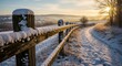 © Sumitra - Winter fence covered in snow at sunrise with sun flare