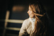 © Emvats - A serene portrait of a young woman with long hair, wearing a white winter jacket, looking away from the camera into the warm sunlight. Her hair catches the light beautifully, creating a soft, dreamy a