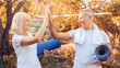 © Prostock-studio - A joyful senior couple shares a high-five after finishing their outdoor yoga practice in a park surrounded by vibrant autumn leaves. They hold yoga mats and wear comfortable clothes.
