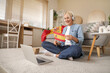 © Pixel-Shot - Mature woman in headphones with flag of Spain learning language online at home