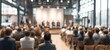 © hao - Business experts give presentation to audience in modern conference hall. Attendees listen attentively to speakers on stage. Blurred background suggests large room with windows urban view. Likely