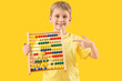 © Pixel-Shot - Cute little boy pointing at abacus on yellow background