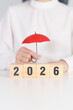 © Jo Panuwat D - Happy New Year 2026 with hand holding red umbrella. Insurance, protection, safety and New year holiday Concepts